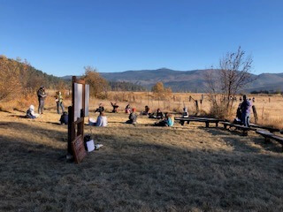 View of students sitting on the ground and writing at their outdoor classroom