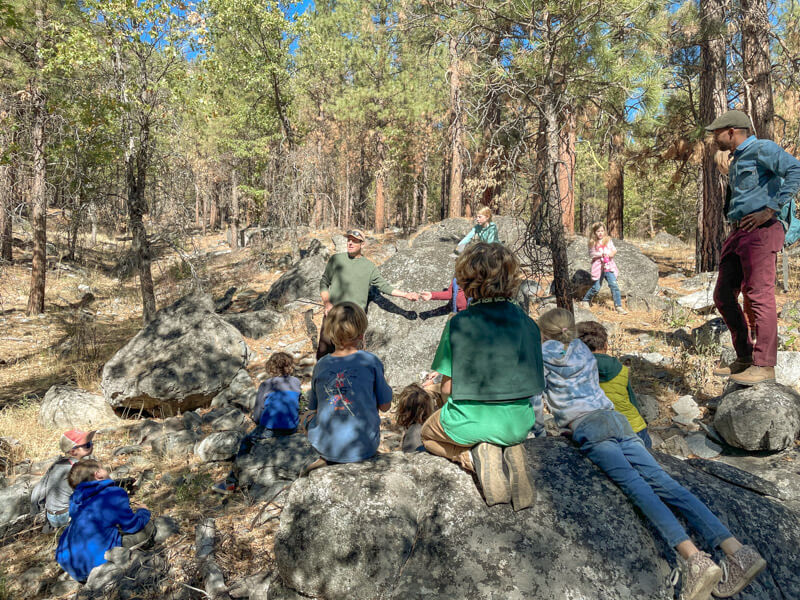 Group of elementary students sit on rocks on the Heart K Ranch in Genesee Valley