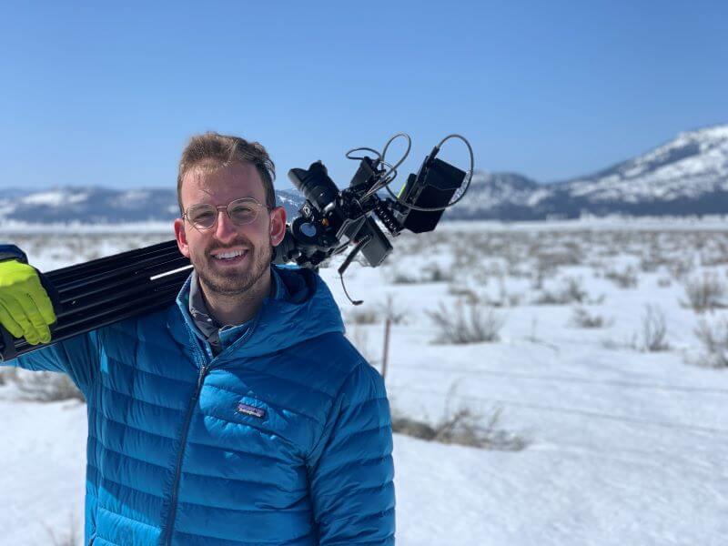 Photographer and videographer Alex Rubenstein stands in snowy Sierra Valley with his camera gear